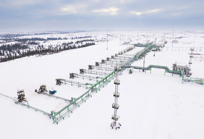 Трубопроводы на нефтяном промысле в заснеженной тундре, вид сверху